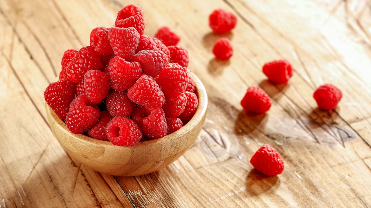 Raspberries on a wooden table on a beautiful sunny day 