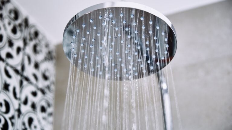 Modern shower with falling water drops in bathroom, closeup