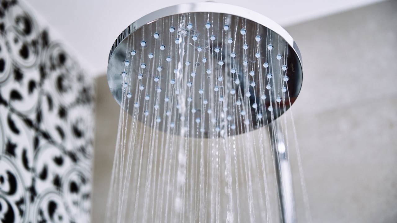 Modern shower with falling water drops in bathroom, closeup