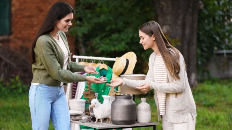 Women shopping at table in yard. Garage sale