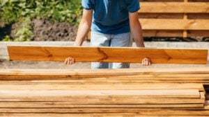 Adult man assembling a modern wooden fence