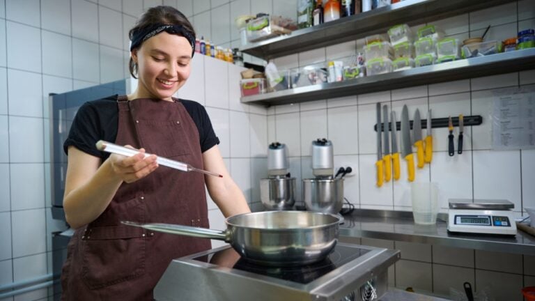 Joyous chef preparing to measure temperature of liquid during food preparation