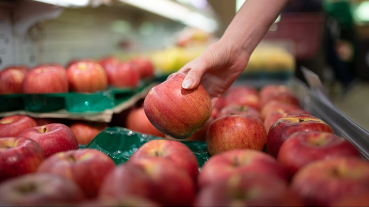 Hands choosing apples in a Japanese supermarket