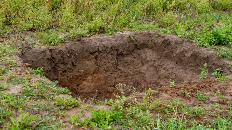 deep excavation site in earth, showcasing preparations for underground utility repairs, agricultural storage, silage pit or grave site, groundwork preparation