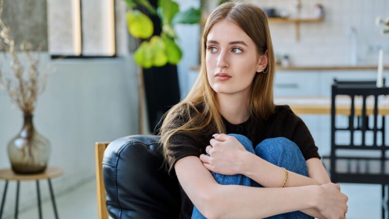Sad unhappy thoughtful young woman sitting in armchair at home