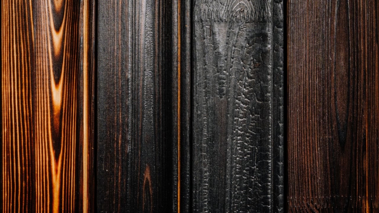 Close-up of various burnt wood planks showing unique textures and tones from charred to polished, emphasizing the natural grain and craftsmanship.