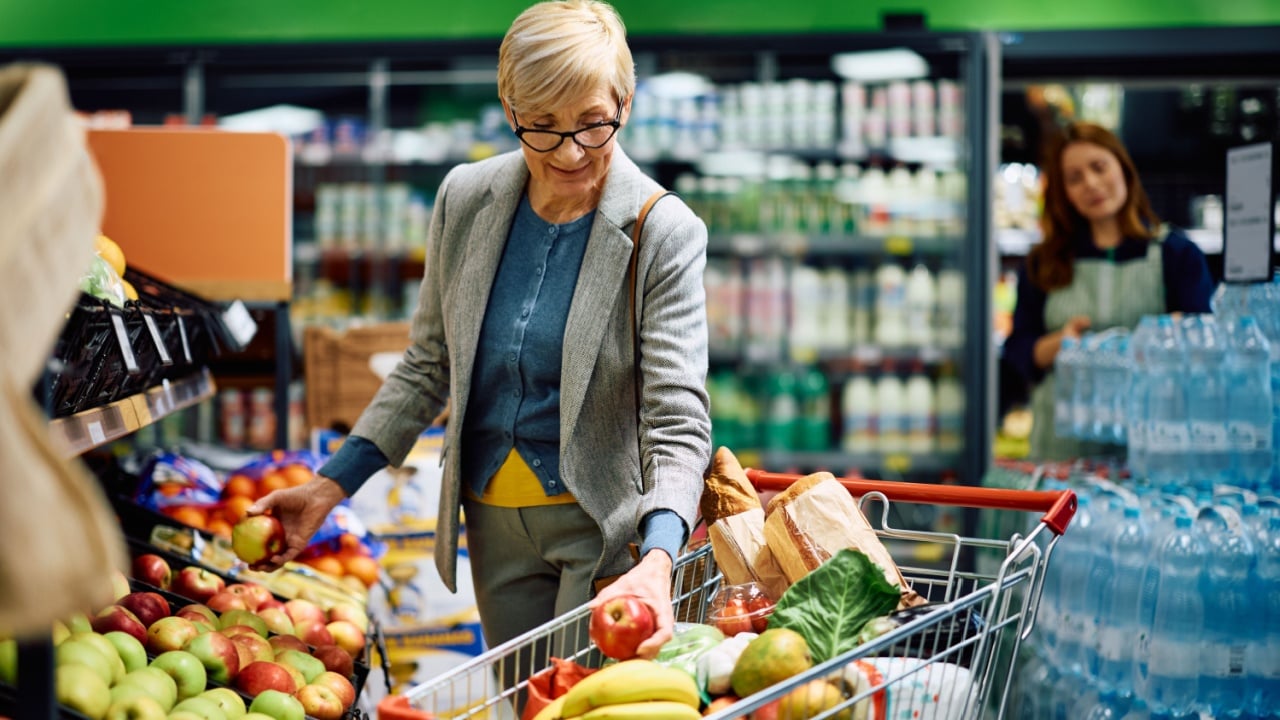 Senior woman buying at fresh fruit section in a supermarket.