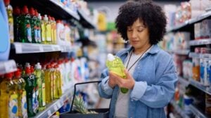 Mature woman reading label on package while buying groceries at supermarket.