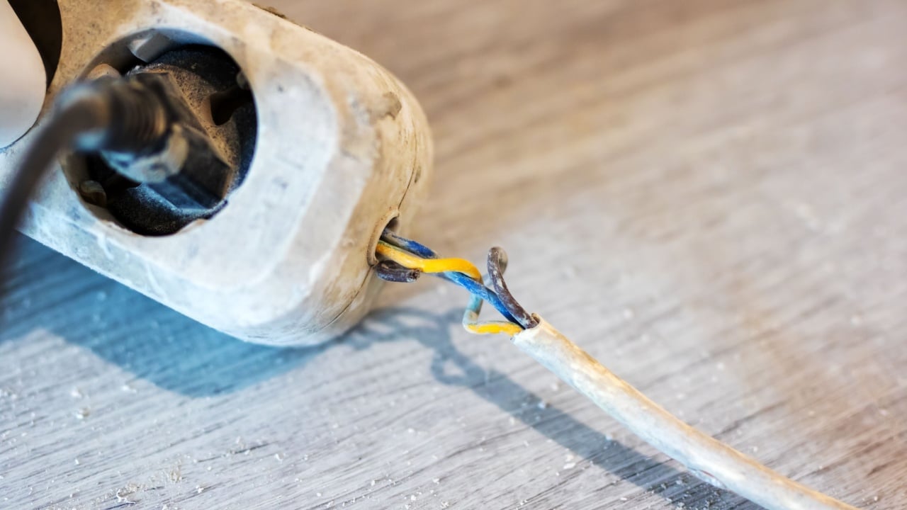 A damaged electrical cord is currently plugged into a power strip, which can create a significant safety hazard for users near it