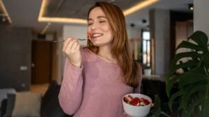 Young woman savoring the taste of fresh strawberries in the comfort of her modern home, enjoying a healthy and delicious snack or breakfast