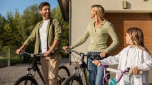 Family with bikes preparing for ride outside modern house garage