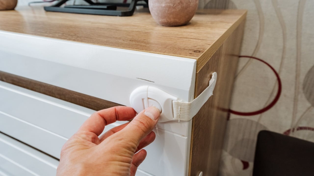 A diligent person is carefully and securely fastening a sturdy lock onto a beautifully crafted wooden dresser, ensuring the utmost safety and organization of its precious and valuable contents inside