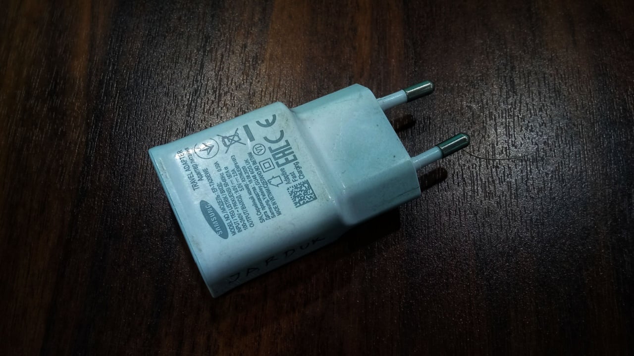 Karawang, Indonesian, October 22, 2025: Close-up of a white Samsung travel charger adapter resting on a dark wooden surface.