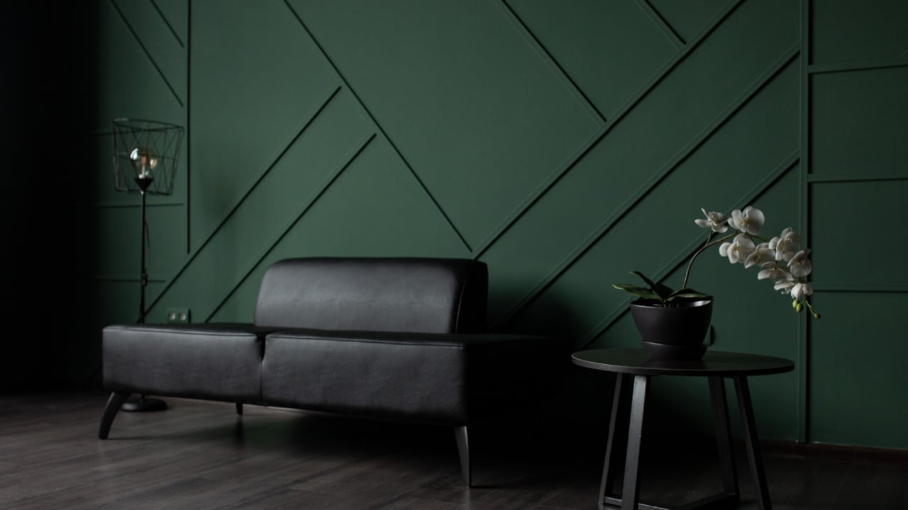Moody lounge with dark green geometric wall and black sofa