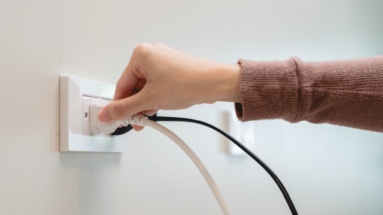 Close-up hands pull off electronic device plug after finish used.