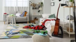 Interior of messy teenager's room with bed, shelf units and sofa