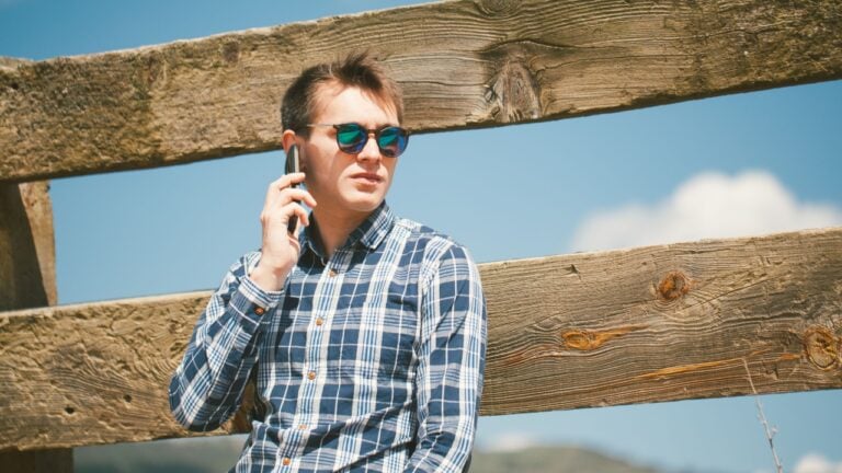 Young man calling by cell phone in the countryside.