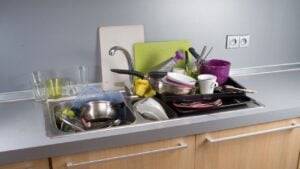 Many dirty dishes in the kitchen sink, more from left, horizontal.