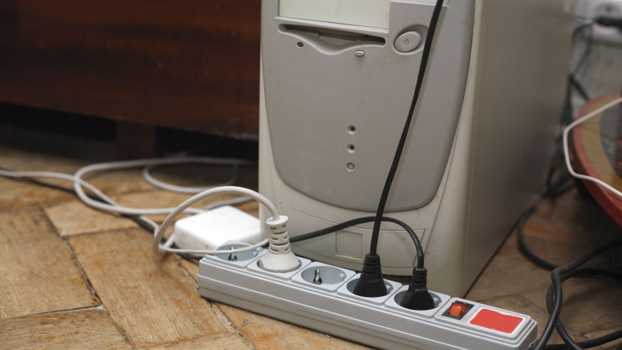 Electric extension, cables and adaptors on the wooden floor next to computer