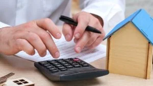Man calculating mortgage payment, insurance or property tax on calculator close up. Expenses on refinancing of home loan. Real estate investment concept