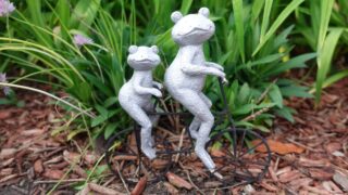 Garden ornament of two frog sitting on a bike.