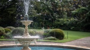 A classic stone fountain sprays water in a tranquil garden setting.
