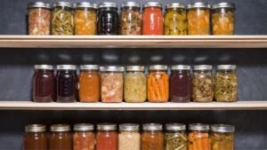 Canned goods on wooden shelves against a chalkboard.