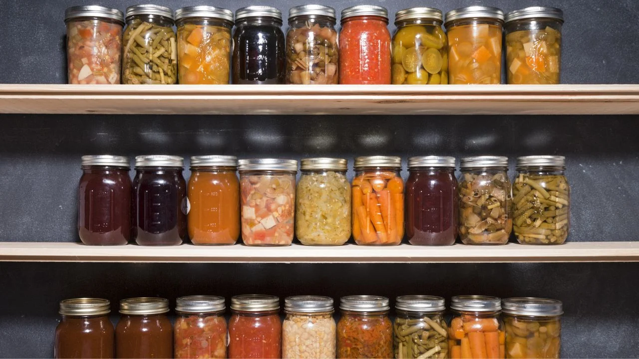 Canned goods on wooden shelves against a chalkboard.