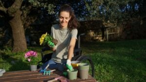 Disabled woman enjoying gardening, planting flowers from pots, showing inclusion and hobby