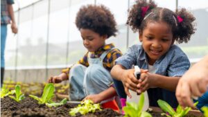 Happy African farmer family on agriculture farm growing organic vegetable together in greenhouse garden.
