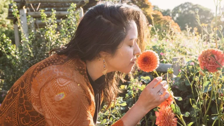 A woman smelling a flower in a garden.