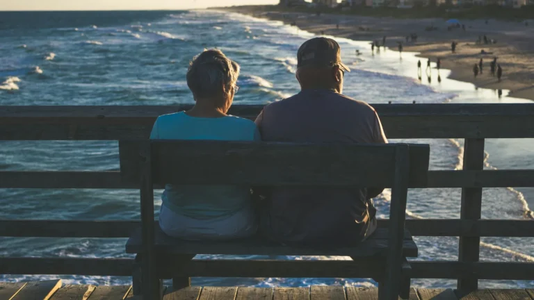 Retired couple sits on pier.